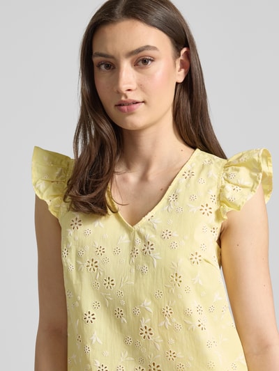 Frauenmodel trägt Regular Fit Blusentop aus reiner Baumwolle Modell 'BANNA' von Pieces, gelb mit floralem Allover-Muster, Nahaufnahme Oberkörper.