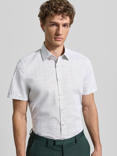 Männermodel trägt Slim Fit Business-Hemd mit Kentkragen von OLYMP Level Five, Baumwoll-Mix mit Stretch-Anteil, Knopfleiste, abgerundeter Saum, Rückenlänge bei Größe 40: 80 cm, Schulterbreite 40 cm, Ärmellänge 25 cm, heller Print, Ganzkörperansicht von vorne.