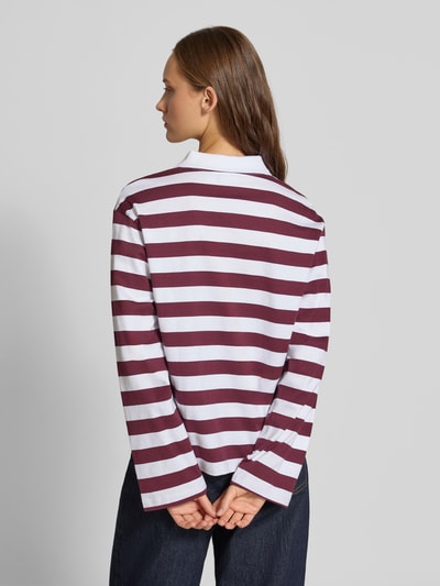 Frauenmodel trägt Relaxed Fit Poloshirt aus reiner Baumwolle Modell 'Dollie' von NOISY MAY®, breite weiße und bordeauxrote Streifen, langärmelig, Polokragen, Rückenansicht, Ganzkörperansicht Rückansicht.