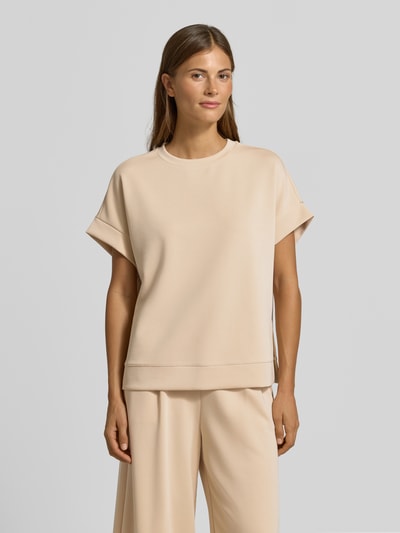 Frauenmodel trägt T-Shirt mit elastischen Abschlüssen von Rich & Royal in Beige, Relaxed Fit, glatte Textur, Nahaufnahme Oberkörper, Modal-Mix mit Stretch-Anteil, Rundhalsausschnitt.