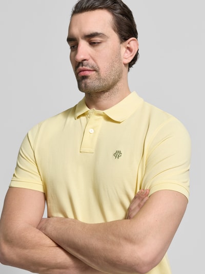 Männermodel trägt Slim Fit Poloshirt mit Logo-Stitching von MCNEAL, gele katoen, polokraag, lichtgeel, nahaufnahme oberkörper.