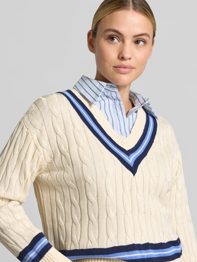 Frauenmodel trägt Regular Fit Pullover aus reiner Baumwolle von MANGO, Strick-Optik, V-Ausschnitt, beige mit blauen Streifen, Nahaufnahme Oberkörper.