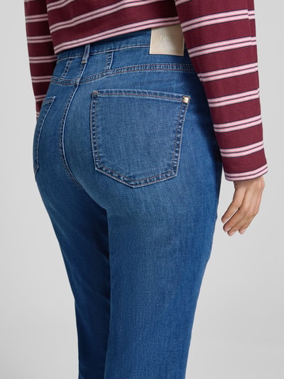 Frauenmodel trägt Bootcut Jeans im 5-Pocket-Design Modell 'Mary' von Brax aus blauem Baumwoll-Mix mit Stretch-Anteil, Label-Detail, Nahaufnahme Rückansicht.