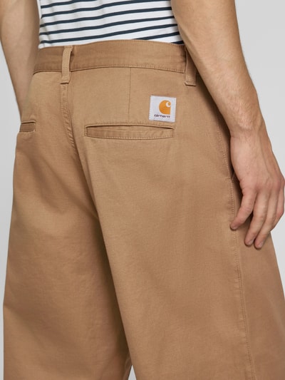 Männermodel trägt Relaxed Fit Stoffhose mit Baumwoll-Anteil Modell 'Brady' von Carhartt Work In Progress, braun, Hinteransicht, Nahaufnahme Oberkörper, Herren Stoffhose, Material-Mix, Gürtelschlaufen, Eingriff- und Gesäßtaschen.