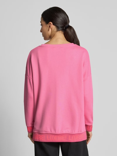 Vrouwenmodel draagt Oversized sweatshirt uit puur katoen Model 'L(I)EBE' van miss goodlife in felroze met ribboordjes, pailletten en statementprint, volledige rugaanzicht.