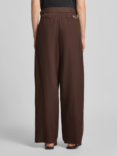 Frauenmodel trägt Wide Leg Hose mit Eingrifftaschen Modell 'QUINN' von Scotch & Soda in Braun, Baumwoll-Leinen-Mix, Ganzkörperansicht Rückansicht.