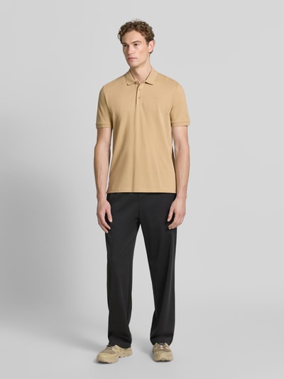 Männermodel trägt regular fit poloshirt aus puur katoen Modell 'DONOS222' van HUGO in beige met zwarte broek, heren, ganzlichaamsvooraanzicht.