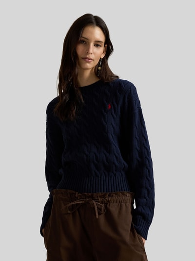 Modelka nosi Regular Fit Strickpullover aus reiner Baumwolle od Polo Ralph Lauren, ciemny granat, wzór warkoczowy, logo, bawełniany sweter, widok z przodu na górną część ciała.