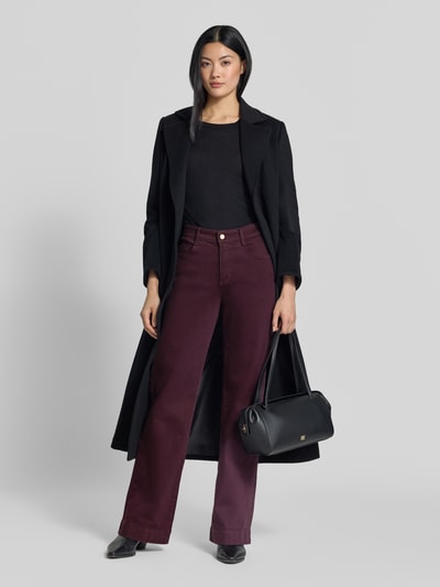 Frauenmodel trägt Wide & Loose Fit Jeans aus Baumwoll-Mix Modell 'Maine' von Brax in Dunkelrot, kombiniert mit schwarzem Mantel, Damen Wide & Loose Fit Jeans von Brax, Ganzkörperansicht von vorne.
