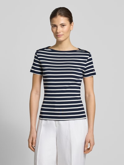 Frauenmodel trägt Slim Fit T-Shirt aus reiner Baumwolle von Tommy Hilfiger, navy-weiß gestreift, kurzarm, U-Boot-Ausschnitt, Logo-Detail, Ganzkörperansicht von vorne.