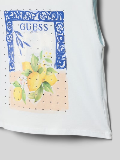 Meisje draagt T-shirt met motiefprint en strass-steentjes van Guess, puur katoen, boxy fit, ronde hals, ruglengte maat 140: 43 cm, detailopname.