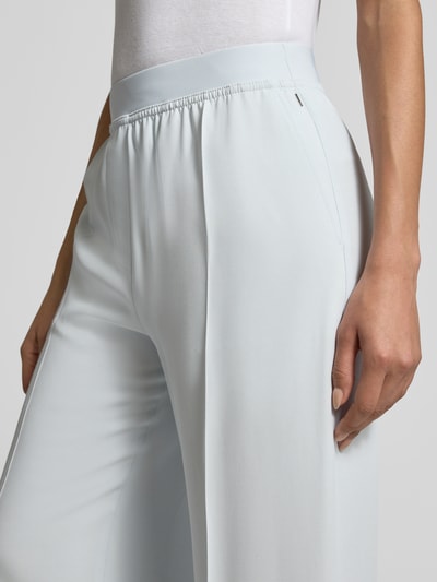 Frauenmodel trägt Weite Hose aus reiner Viskose Modell 'TIANA10' von BOSS in Hellblau, unifarben, elastischer Bund, seitliche Eingrifftaschen, Nahaufnahme Hüfte.