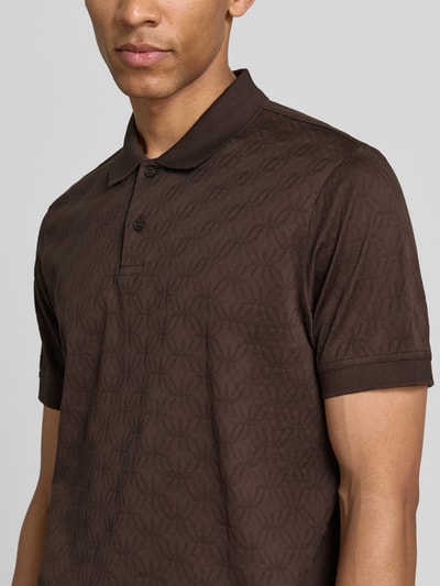 Męski model nosi Modern Fit Poloshirt mit Strukturmuster Modell 'Roberto' od JOOP! Collection, brązowa bawełna, detal z logo, krój modern fit, widok na górną część tułowia z przodu.
