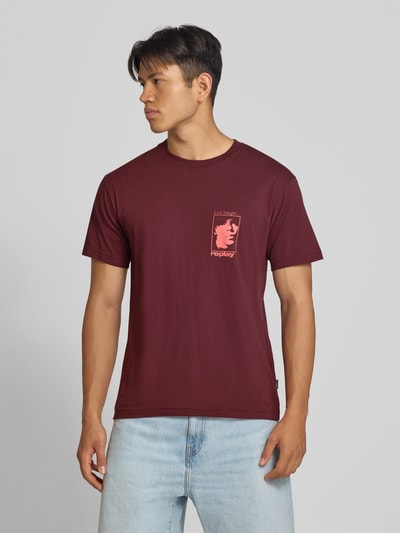 Männermodel trägt T-Shirt mit Motiv-Print und Rundhalsausschnitt von Replay, reine Baumwolle, Regular Fit, bordeaux, Ganzkörperansicht von vorne.