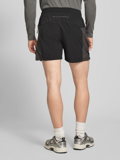 Männermodel trägt schwarze Herren Shorts mit Reißverschlusstaschen Modell 'HALO DIVISION' von HALO, Regular-Fit, elastischer Bund, Ganzkörperansicht Rückansicht.