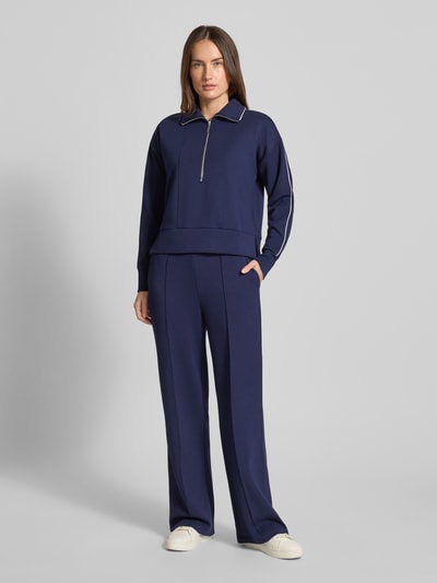 Modelka kobieca nosi Sweatpants mit elastischem Bund od Christian Berg Woman w kolorze granatowym, luźny krój, materiał z domieszką modalu, widoczne kieszenie boczne i tylne, widok całej sylwetki z przodu.