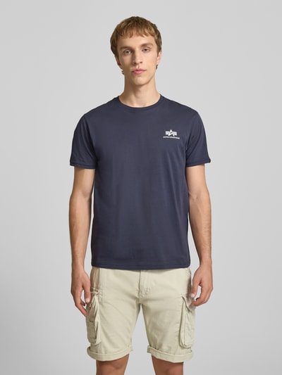 Männermodel trägt T-Shirt mit Logo und Rundhalsausschnitt von Alpha Industries in Dunkelblau, Reine Baumwolle, Regular-Fit, Rückenlänge 67 cm, Ganzkörperansicht von vorne.