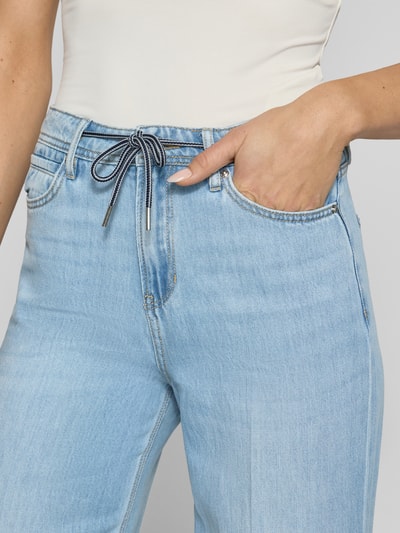 Frauenmodel trägt Wide Leg Jeans aus Lyocell-Baumwoll-Mix Modell 'SURI' von s.Oliver RED LABEL, Denim-Optik, hellblau, 5-Pocket-Design, Tunnelzug, Label-Patch, Nahaufnahme Oberkörper