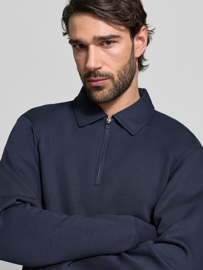 Männermodel trägt Regular Fit Poloshirt aus Viskose-Mix Modell 'EMANUEL' von SELECTED HOMME in Dunkelblau, Nahaufnahme Oberkörper.