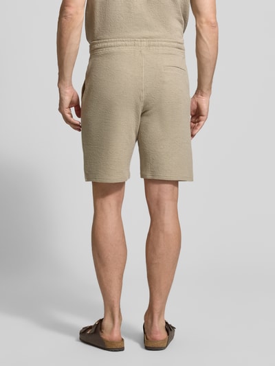 Męski model nosi Regular Fit Poloshirt aus Baumwoll-Mix von MCNEAL, mieszanka bawełny i elastanu, pika, beżowy, wykładany kołnierz, krótki rękaw, długość tyłu w rozmiarze M: 69 cm; kompletna sylwetka z tyłu.