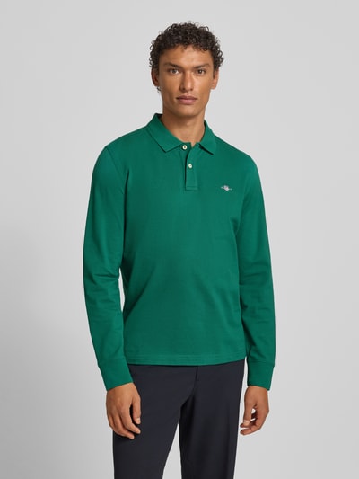 Männermodel trägt Regular Fit Poloshirt mit Label-Stitching von Gant, grün, reine Baumwolle, Polokragen, Knopfleiste, Ganzkörperansicht von vorne. Rückenlänge bei Größe M: 68 cm.