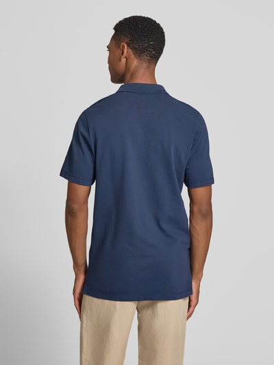 Männermodel trägt Regular Fit Poloshirt aus reiner Baumwolle von s.Oliver RED LABEL, unifarben in Dunkelblau, Piqué-Struktur, Ganzkörperansicht Rückansicht.