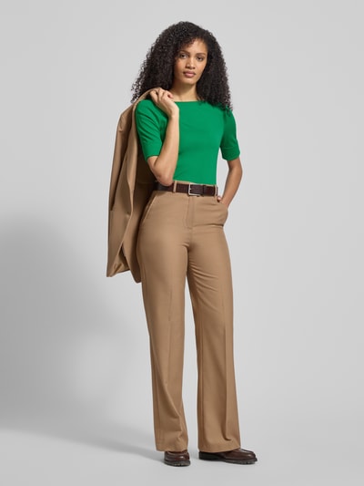 Frauenmodel trägt T-Shirt mit geripptem U-Boot-Ausschnitt Modell 'JUDY' von Lauren Ralph Lauren in leuchtendem Grün, Baumwoll-Elasthan-Mix, Slim Fit, kombiniert mit heller Hose, Rückenlänge bei Größe S 58 cm, Ganzkörperansicht von vorne.