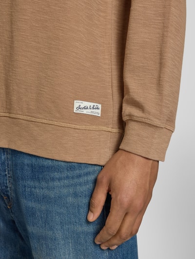 Männermodel trägt Regular Fit Sweatshirt mit Rundhalsausschnitt von Scotch & Soda, katoenmix, labeldetail, detailaufnahme rechter onderarm