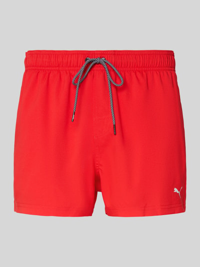 Produktfoto, Badehose mit Seitentaschen und Klettverschlusstasche hinten von PUMA in leuchtendem Rot, elastischer Bund, Regular Fit, auf weiß-grauem Hintergrund.