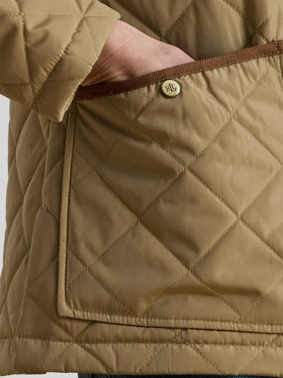 Kobieta nosi Regular Fit Steppjacke mit Umlegekragen od Lauren Ralph Lauren, beżowa, pikowana faktura, naszywana kieszeń z logo, detal, zbliżenie na kieszeń.