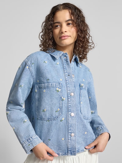 Vrouwenmodel draagt lichtblauwe regular fit jeansjack uit puur katoen model 'CASSIE' van ONLY met wit bloemenpatroon, nahaufnahme bovenlichaam.