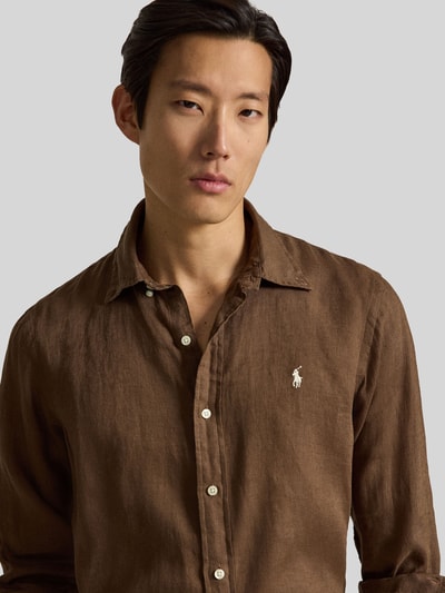 Männermodel trägt Regular Fit vrijetijdsoverhemd uit puur linnen van Polo Ralph Lauren, look: effen, logodetail, materiaal: gevlamd garen, custom fit, button-downkraag, knoopsluiting, lange mouw, sportmanchet, achterpas met cacharel-plooi. Nahaufnahme bovenlichaam.