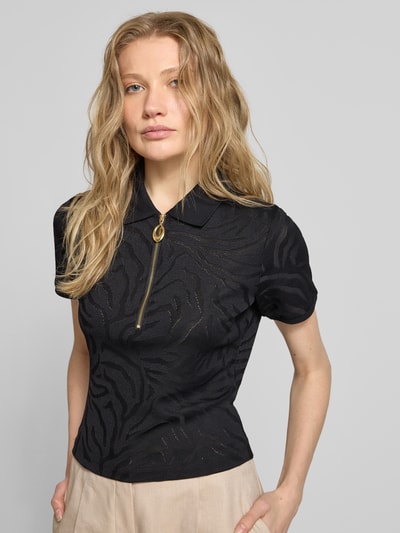 Kobiece modelka trägt Regular Fit Poloshirt aus Viskose-Mix Modell 'DEMETRI' von HUGO w kolorze czarnym, połyskujący animal print, krótki rękaw, półprzezroczysta struktura, złoty zamek z logo, krój regular fit, całkowita widoczność górnej części ciała, widok z przodu.