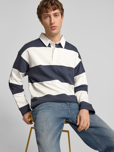 Männermodel trägt Sweatshirt mit Polokragen Modell 'UPSTATE' von Jack & Jones aus reiner Baumwolle, lockerer Schnitt, breite navy-weiße Streifen, kurze Knopfleiste, Rückenlänge 68 cm, Ärmellänge 59 cm, Ganzkörperansicht von vorne.