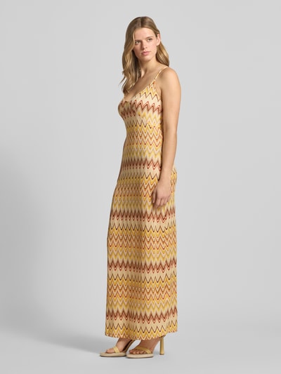 Vrouwenmodel draagt Maxikleid im Allover-Look van Gina Tricot in geelbruin met zigzagpatroon, materiaalmix met stretch, recht model, V-hals, spaghettibandjes, dames maxi-jurk, zijaanzicht, Ganzkörperansicht van voren.