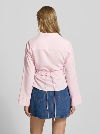 Frauenmodel trägt Leinenbluse mit Bindegürtel und V-Ausschnitt von Gina Tricot im zarten Rosa, Leinen-Baumwoll-Anteil, taillierter Schnitt, Kentkragen, Knopfleiste, Rückansicht, Ganzkörperansicht.