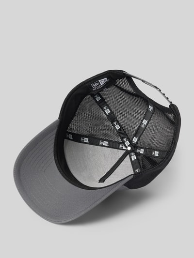 Produktfoto, Trucker Cap mit verstellbarem Riegel auf der Rückseite von New Era in Grau und Schwarz, verstärkter Schirm, Steppnähte, Statement-Applikation, Rückseite im Mesh-Design