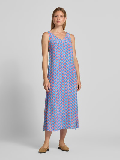 Frauenmodel trägt Midikleid aus Viskose mit V-Ausschnitt von Smith and Soul, Allover-Muster in Blau und Rot, A-Linie, Ganzkörperansicht von vorne.