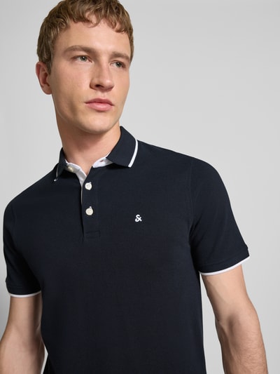 Männermodel trägt Slim Fit Poloshirt mit Viskose-Anteil Modell 'Paulos' von JACK & JONES, Baumwoll-Mix, Logo-Stitching, Nahaufnahme Oberkörper.