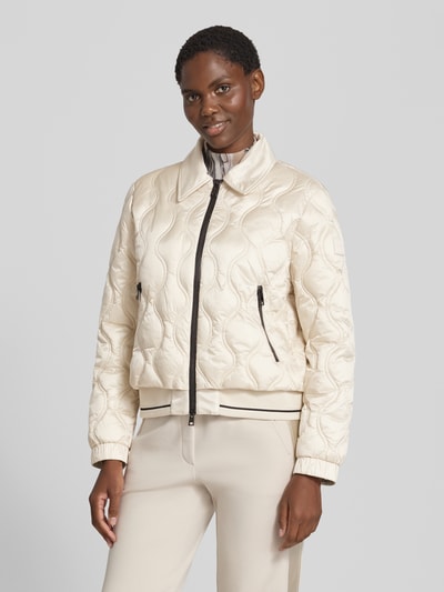 Frauenmodel trägt Steppjacke mit Umlegekragen und Reißverschlusstaschen von Marc Cain in Beige, strukturierte Oberfläche, Regular Fit, Ganzkörperansicht von vorne. Rückenlänge 56 cm, Schulterbreite 45 cm, Brustweite 58 cm, Ärmellänge 61 cm.