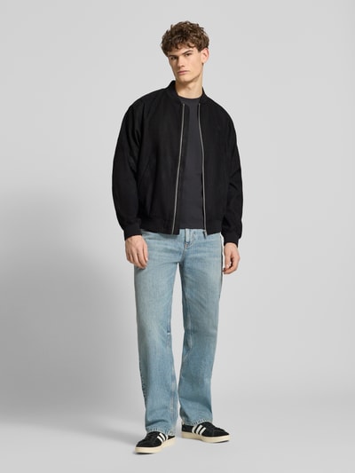 Mannelijk model draagt Bomberjacke mit Reißverschluss van REVIEW in zwart, regular fit, ribboorden, opstaande kraag, rits, steekzakken, label-stitching, ruglengte 68 cm, schouderbreedte 43 cm, borstwijdte 55 cm, mouwlengte 63 cm; kleuren zwart en lichtblauw, rechte vormen, gladde en geribde texturen, full-body voetaanzicht.