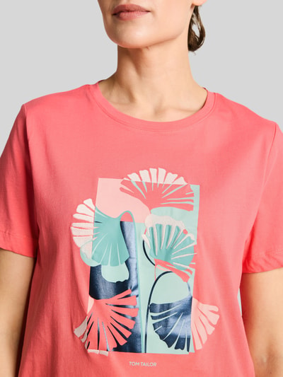 Frauenmodel trägt Regular Fit T-Shirt aus reiner Baumwolle von Tom Tailor in Optik: Unifarben mit Label-Print, Motiv-Print-Stitching, Rundhals-Ausschnitt, Kurzarm, Rumpfabschluss mit Seitenschlitzen, Materialverarbeitung Jersey, Ganzkörperansicht von vorne.