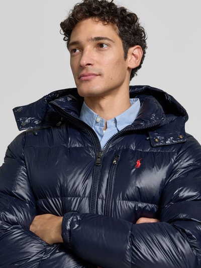 Männermodel trägt dunkelblaue Regular Fit Steppjacke mit Zweiwege-Reißverschluss von Polo Ralph Lauren, glänzende Oberfläche, Nahaufnahme Oberkörper, Herren Steppjacke von Polo Ralph Lauren.
