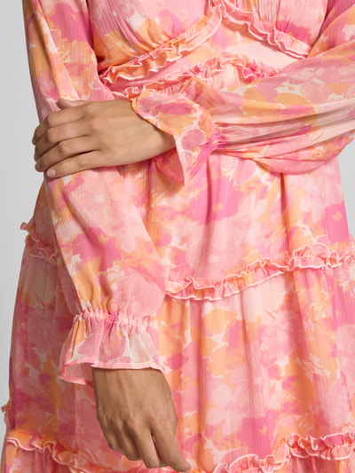 Kobiecy model nosi Regular Fit Sommerkleid aus Chiffon Modell 'SMILLA' od Vero Moda, wzór allover, balonowe długie rękawy, falbany, materiał zwiewny, mini, dekolt V, bez zapięcia; kontekst: letnia sukienka damska, materiał chiffon, detal: frill, widok: zbliżenie na górną część ciała.