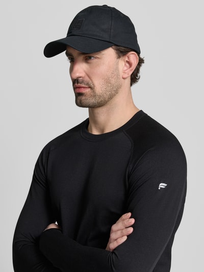 Männermodel trägt Slim Fit Langarmshirt aus atmungsaktivem Material Modell 'TRAINING DAY' von Fabletics, unifarben, reflektierender Logo-Print, rundhals, langarm, schweißregulierend, anti-geur technologie, 4-weg stretch, lichtgewicht, Nahaufnahme Oberkörper.