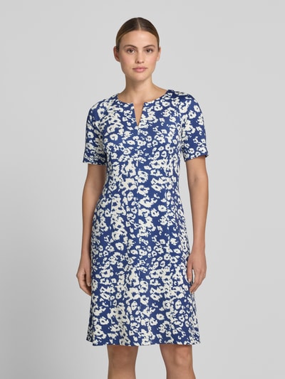 Frauenmodel trägt Knielanges Kleid im Allover-Look mit V-Ausschnitt von Marc Cain im blauen und weißen Blumenmuster, Material-Mix mit Stretch-Anteil, A-Linie, Knielänge, Ganzkörperansicht von vorne. Rückenlänge 93 cm, Brustweite 39 cm, Ärmellänge 30 cm, Größe 36.