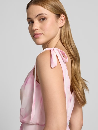 Frauenmodel trägt Knielanges Cocktailkleid mit floralem Allover-Print von Jake*s Cocktail in Rosa mit Zierschleifen, Blickdichter Unterrock, Taillierte Passform, Ärmelloses-Design, floraler Allover-Print, Nahaufnahme Oberkörper.