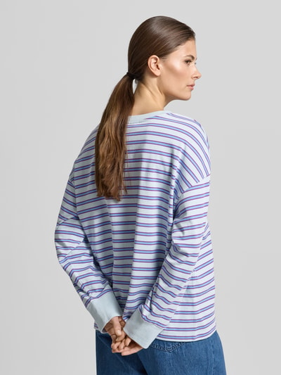 Frauenmodel trägt Longsleeve mit Streifenmuster - curated by Tinvcb von SIC, lila-blau gestreift, lockerer Schnitt, Ganzkörperansicht Rückansicht.