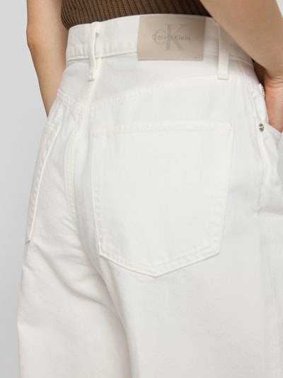 Frauenmodel trägt Wide Leg Jeans aus reiner Baumwolle von Calvin Klein Jeans in weißer Denim-Optik mit Label-Patch, 5-Pocket-Design, Nahaufnahme Rückansicht.