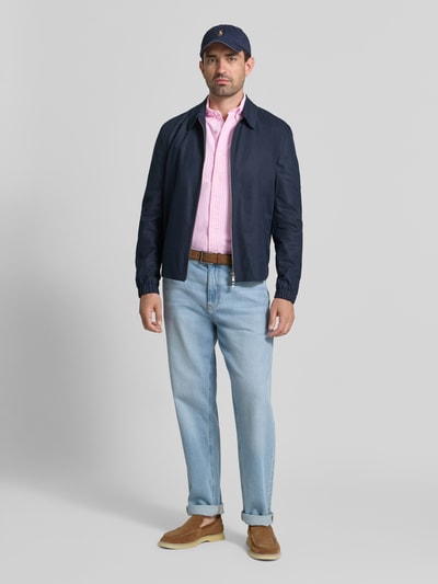 Männermodel trägt Regular Fit Freizeithemd aus reiner Baumwolle von Polo Ralph Lauren in hellrosa, kombiniert mit Jeans, Ganzkörperansicht von vorne.
